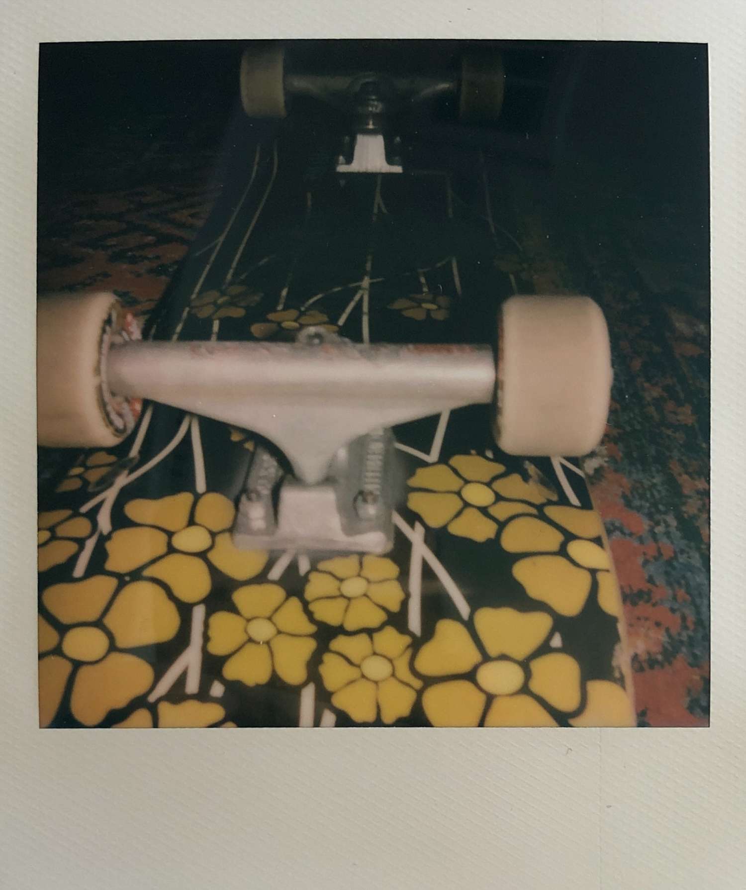 A Polaroid photo of my skateboard laying on a rug in my apartment